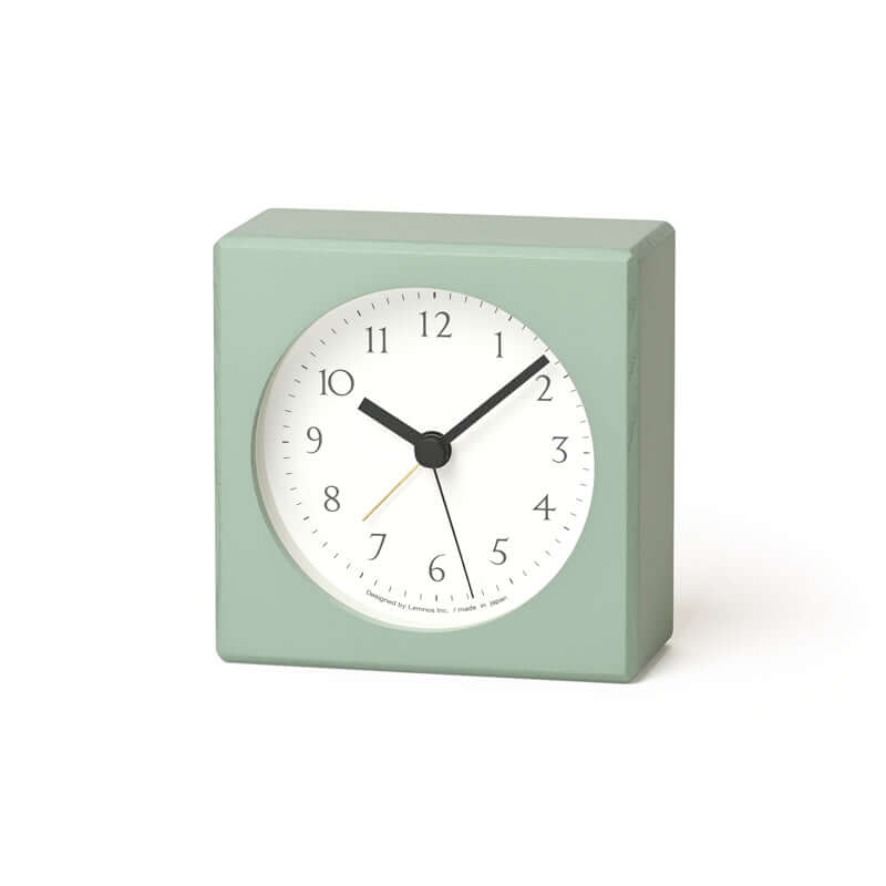 Light green square clock with a white face on a white background