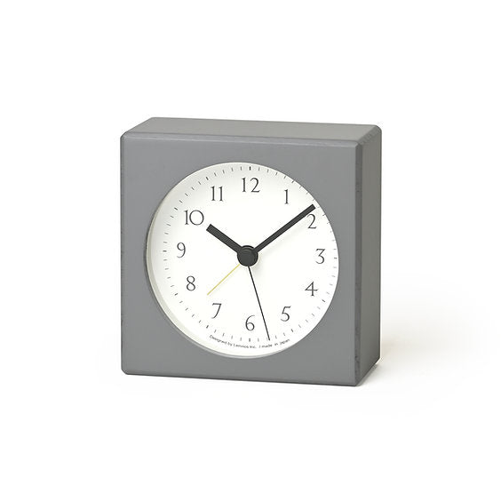 Gray square clock with a white face on a white background