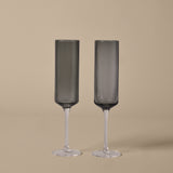 Two ribbed champagne flutes on a beige background