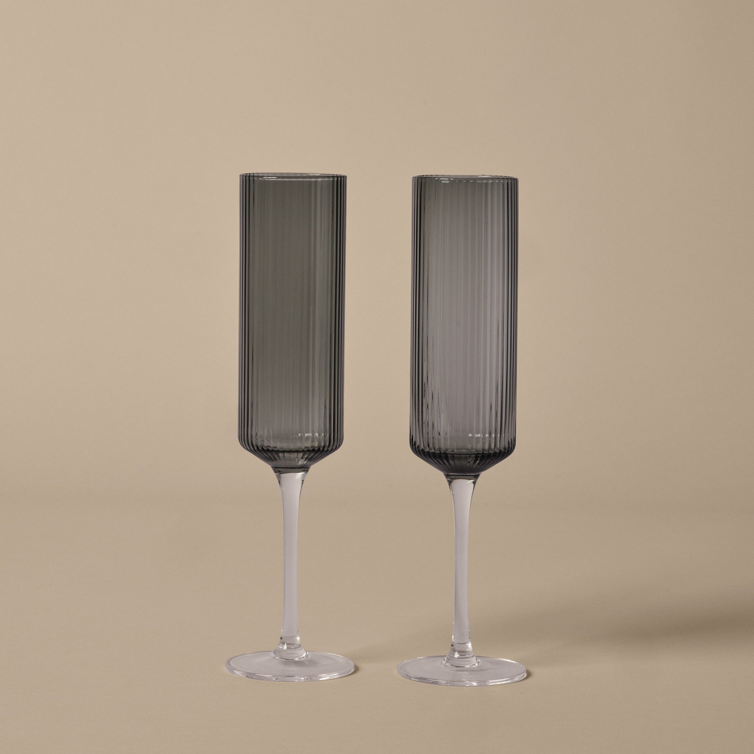 Two ribbed champagne flutes on a beige background