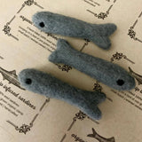Three gray felted fish toys on a textured paper background with text.