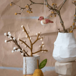 Handmade felt pear ornament and bird on branches, perfect for cozy, sustainable decor in Easter tablescapes.