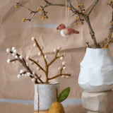 Handmade felt pear ornament and bird on branches, perfect for cozy, sustainable decor in Easter tablescapes.