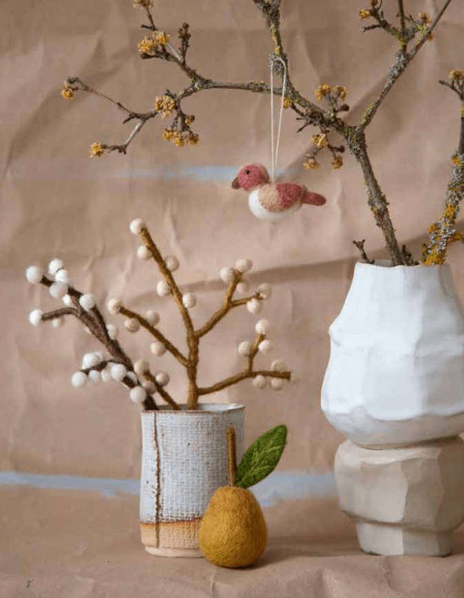 Handmade felt pear ornament and bird on branches, perfect for cozy, sustainable decor in Easter tablescapes.