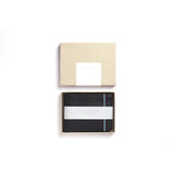 black leather wallet with blue and red elastic inside of a gift box, with paper sleeve around wallet stating Carre Royal. The light brown box cover is shown above the wallet.