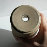 Underside view of Hasami Porcelain small planter showcasing its textured surface and label, balanced in a hand.