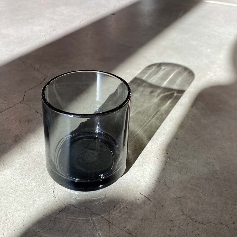 Hasami Porcelain glass tumbler in grey on a concrete surface, showcasing its sleek design and shadow.