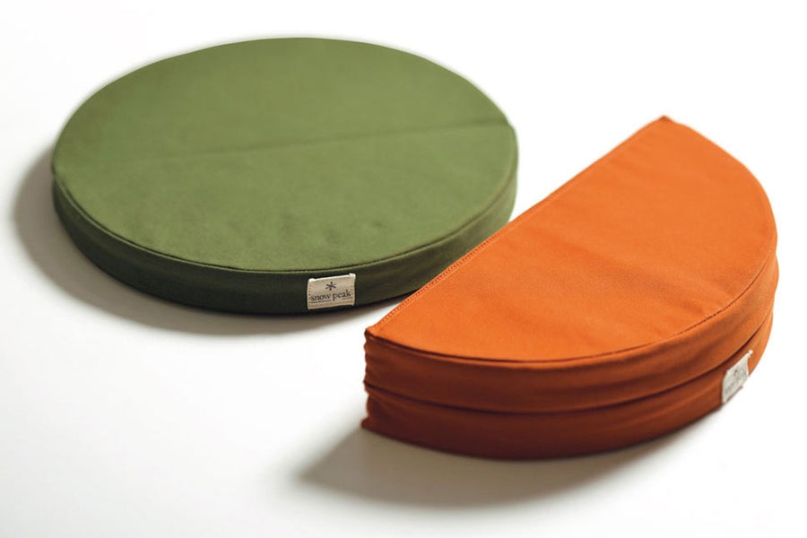 snow peak cushions in green and orange. green cushion is unfolded and the orange is folded in half. 