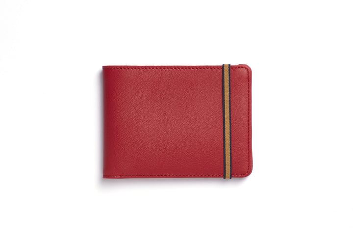 Red rectangular leather wallet with light brown elastic strap around one end.
