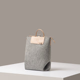 A stylish Bedford Merino Wool Felt Midi Backpack in light gray, displayed in a three-quarter view on a white base