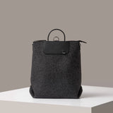 A Bedford Merino Wool Felt Backpack in dark gray standing on a white base, front view