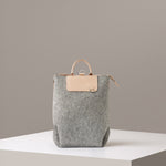A Bedford Merino Wool Felt Midi Backpack in light grey standing on a white base, front view