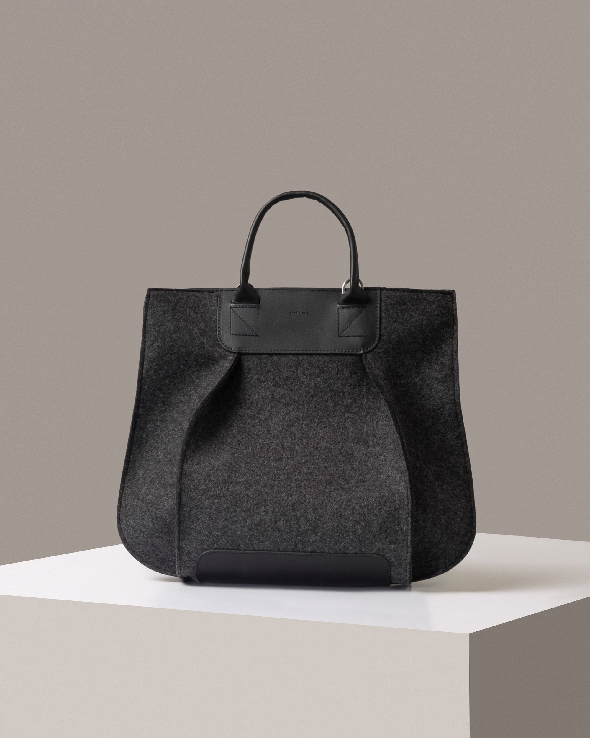 A timeless tote bag, Franke-collection by Graf Lantz, from Merino Wool in charcoal standing on a white base, front view