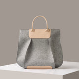 A grey Frankie Merino Wool Felt Tote bag standing on a white base, front view