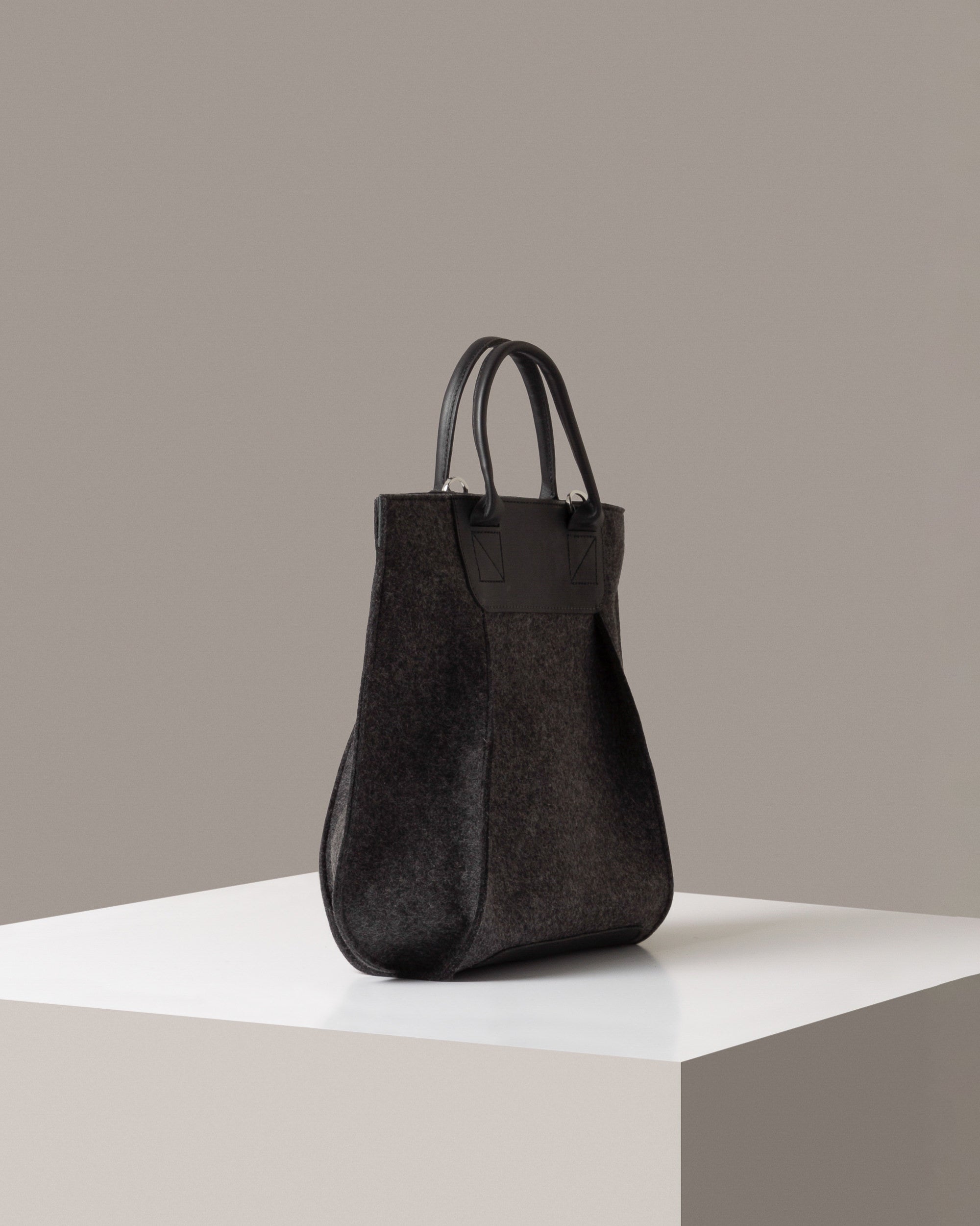 A charcoal Frankie Merino Wool Tote on a white base displayed in a side-view
