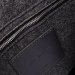 Interior view of dark grey Bedford Merino Wool Felt Backpack featuring a zippered felt pocket, black leather trim, and nickel hardware, highlighted in detail