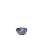 A tiny rounded ceramic bowl in a cool medium blue color featuring iron speckles and an unglazed rim