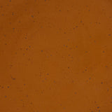A closeup of a ceramic plate in a glossy caramel brown color with iron speckles throughout