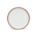 A dinner sized ceramic plate in a cool white color featuring iron speckles and an unglazed rim.