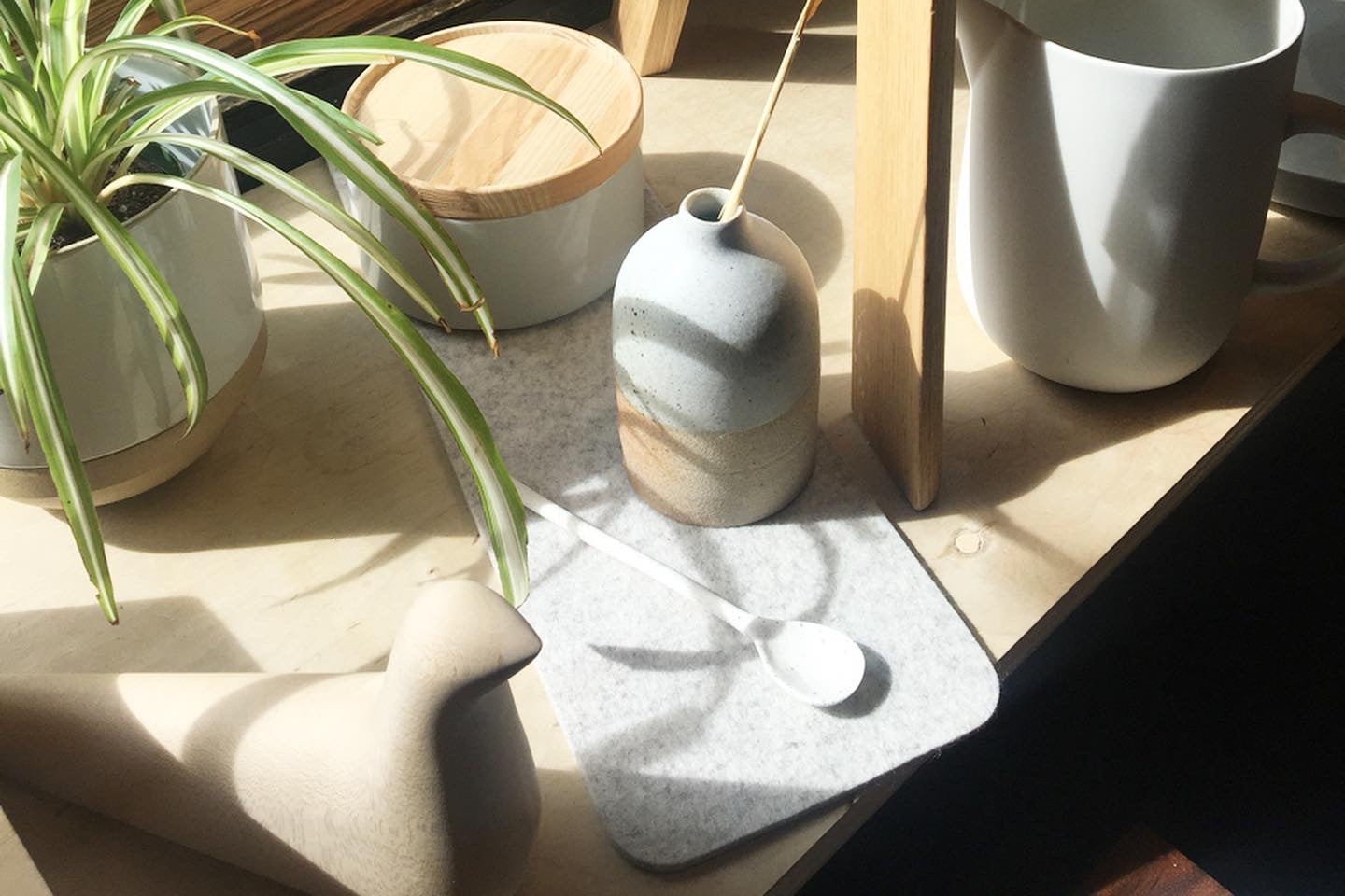 Sunny shelf near window with vases, planters, and other objects