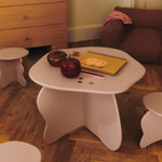 White children's table with toys on a wooden floor in a room with furniture.