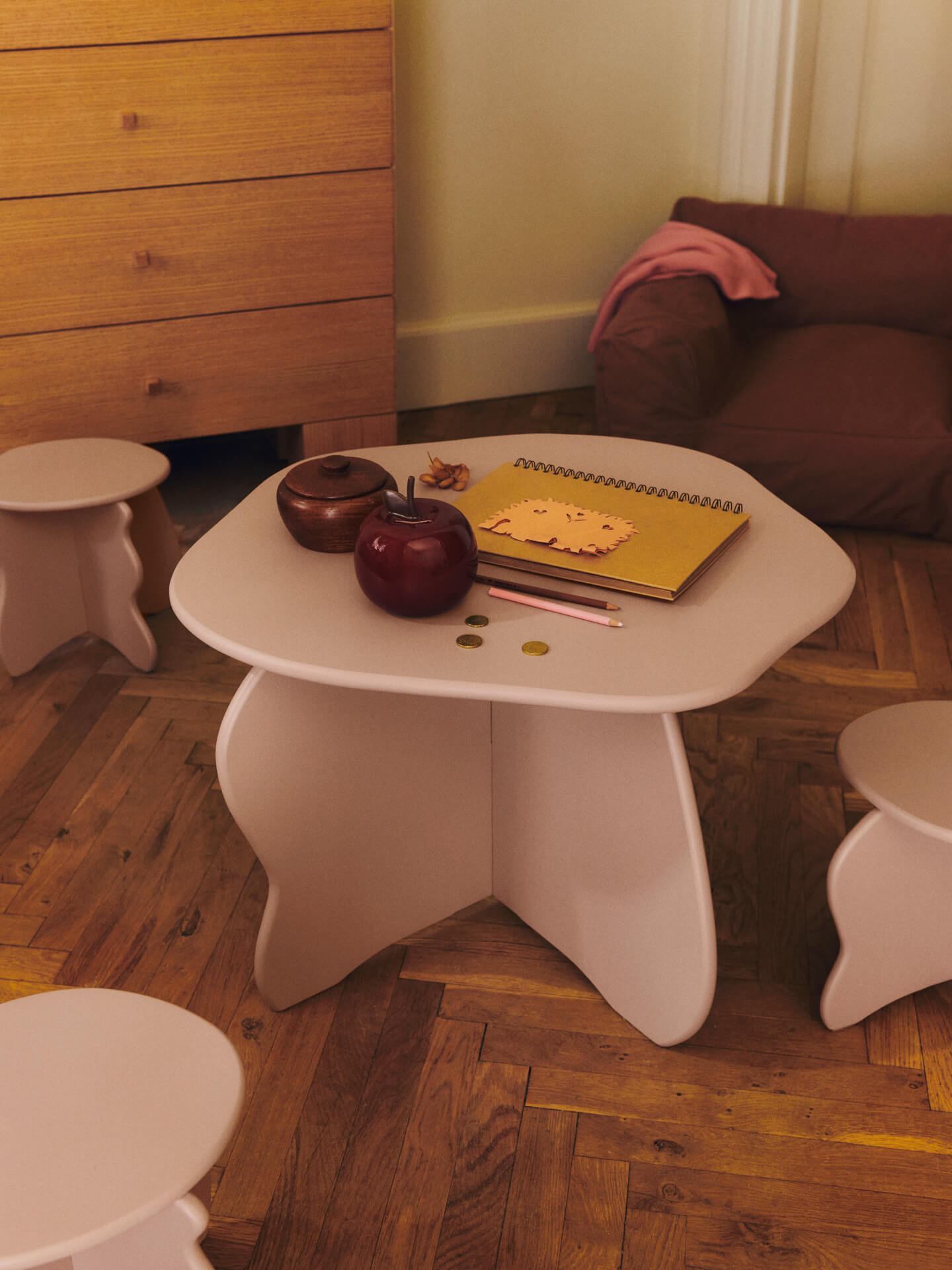 White children's table with toys on a wooden floor in a room with furniture.