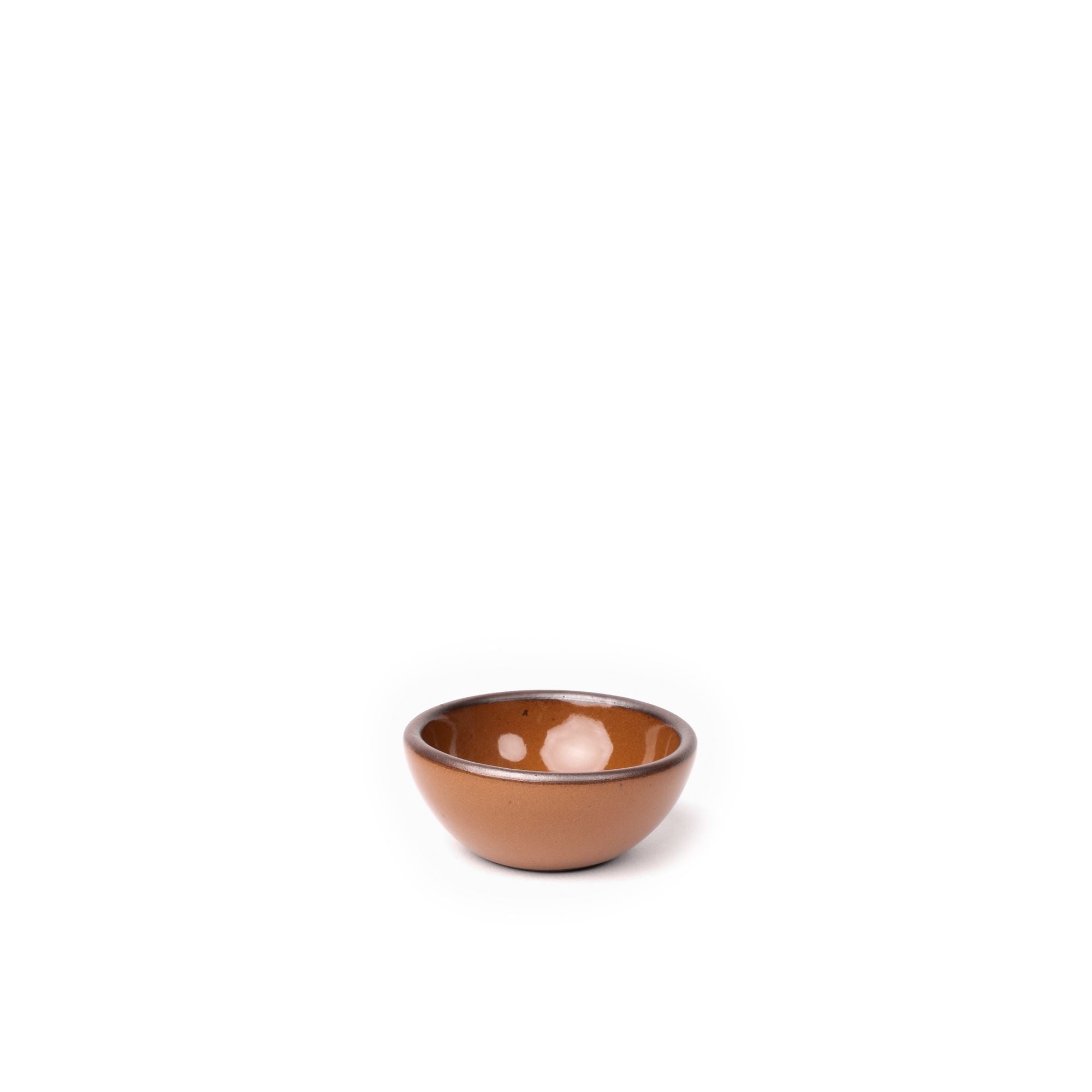 A tiny rounded ceramic bowl in a glossy caramel brown color featuring iron speckles and an unglazed rim