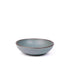 A dinner-sized shallow ceramic bowl in a blue-grey color featuring iron speckles and an unglazed rim