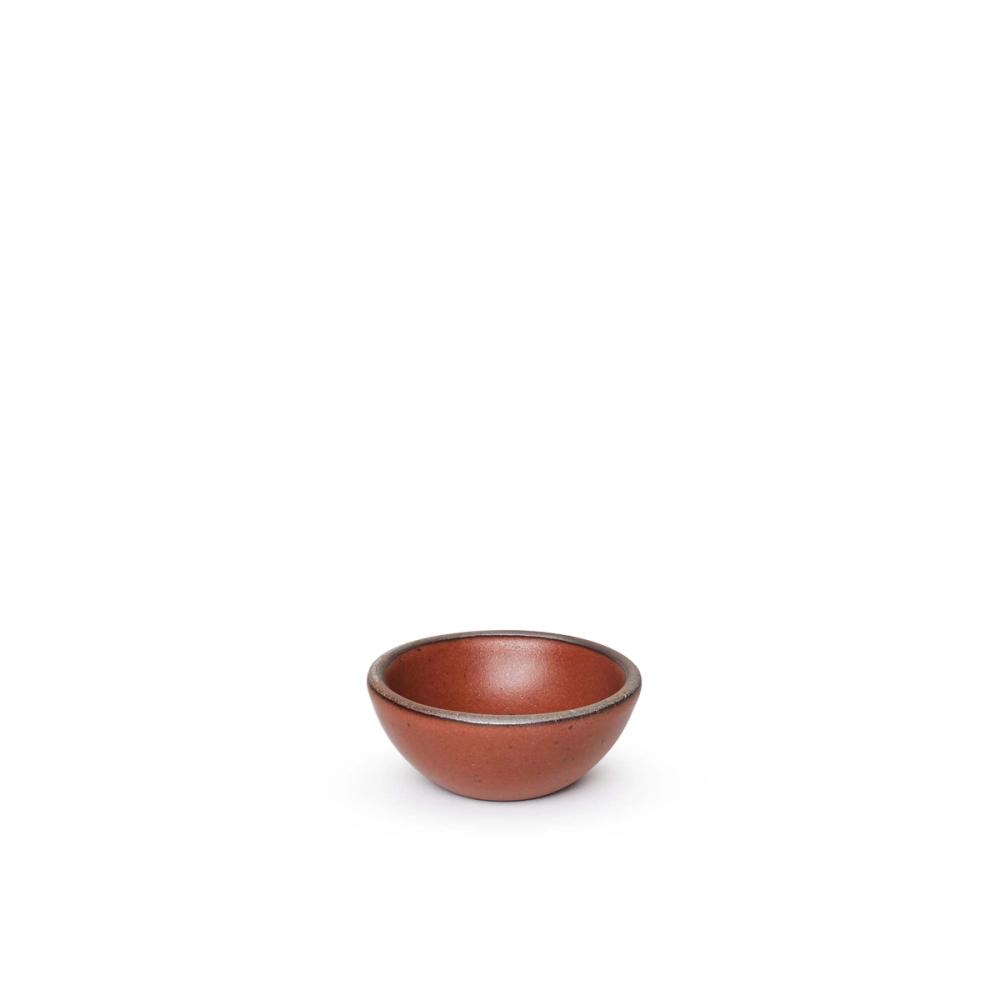 A tiny rounded ceramic bowl in a cool burnt terracotta color featuring iron speckles and an unglazed rim