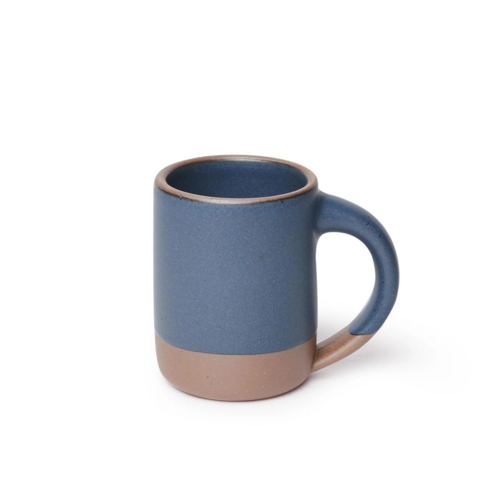 A medium sized ceramic mug with handle in a cool medium blue color featuring iron speckles and unglazed rim and bottom base.