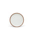A dessert sized ceramic plate in a cool white color featuring iron speckles and an unglazed rim.