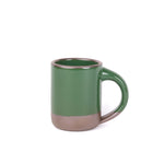 A medium sized ceramic mug with handle in a glossy emerald green color featuring iron speckles and unglazed rim and bottom base.