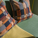 Plaid patterned pillows on a green sofa next to yellow throw. 