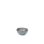 A tiny rounded ceramic bowl in a blue-grey color featuring iron speckles and an unglazed rim