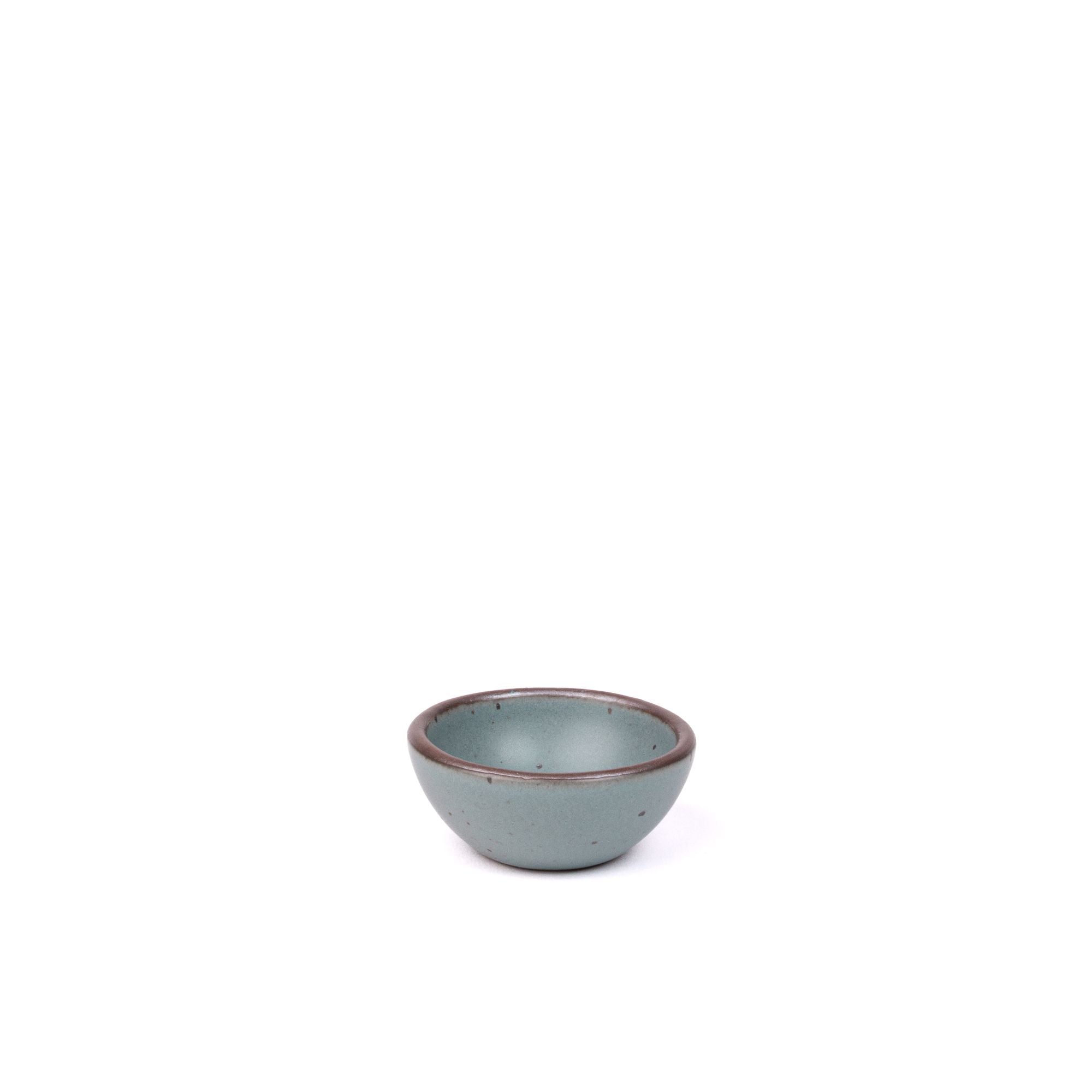 A tiny rounded ceramic bowl in a blue-grey color featuring iron speckles and an unglazed rim
