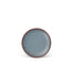 A dessert sized ceramic plate in a blue-grey color featuring iron speckles and an unglazed rim