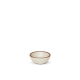 A tiny rounded ceramic bowl in a warm, tan-toned, off-white color featuring iron speckles and an unglazed rim
