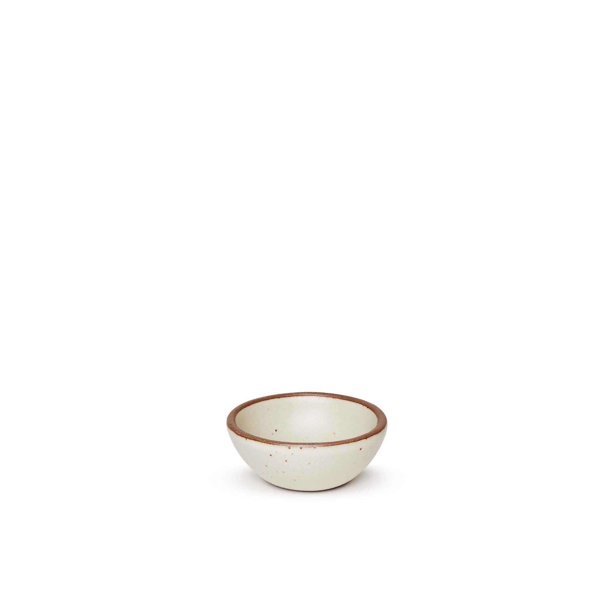 A tiny rounded ceramic bowl in a warm, tan-toned, off-white color featuring iron speckles and an unglazed rim