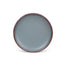 A dinner sized ceramic plate in a blue-grey color featuring iron speckles and an unglazed rim