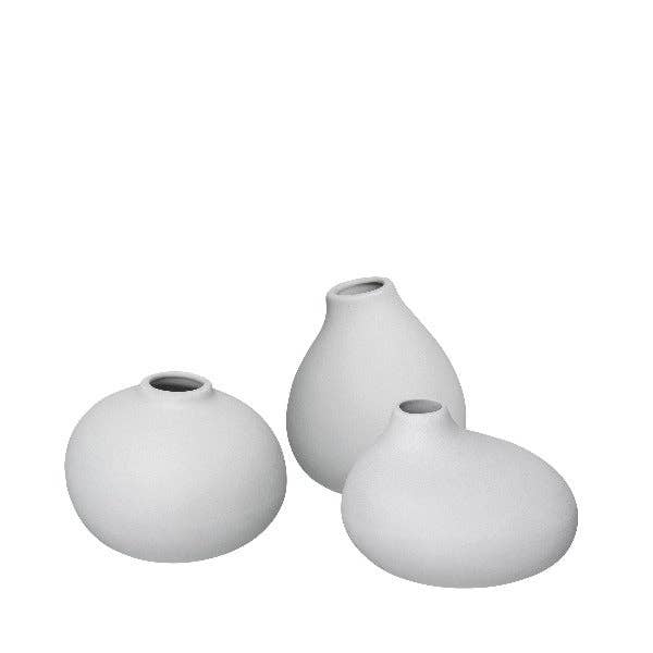 Three light grey ceramic vases of different shapes on a white background