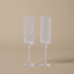 Two clear fluted glasses on a beige background