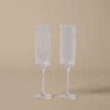 Two clear fluted glasses on a beige background