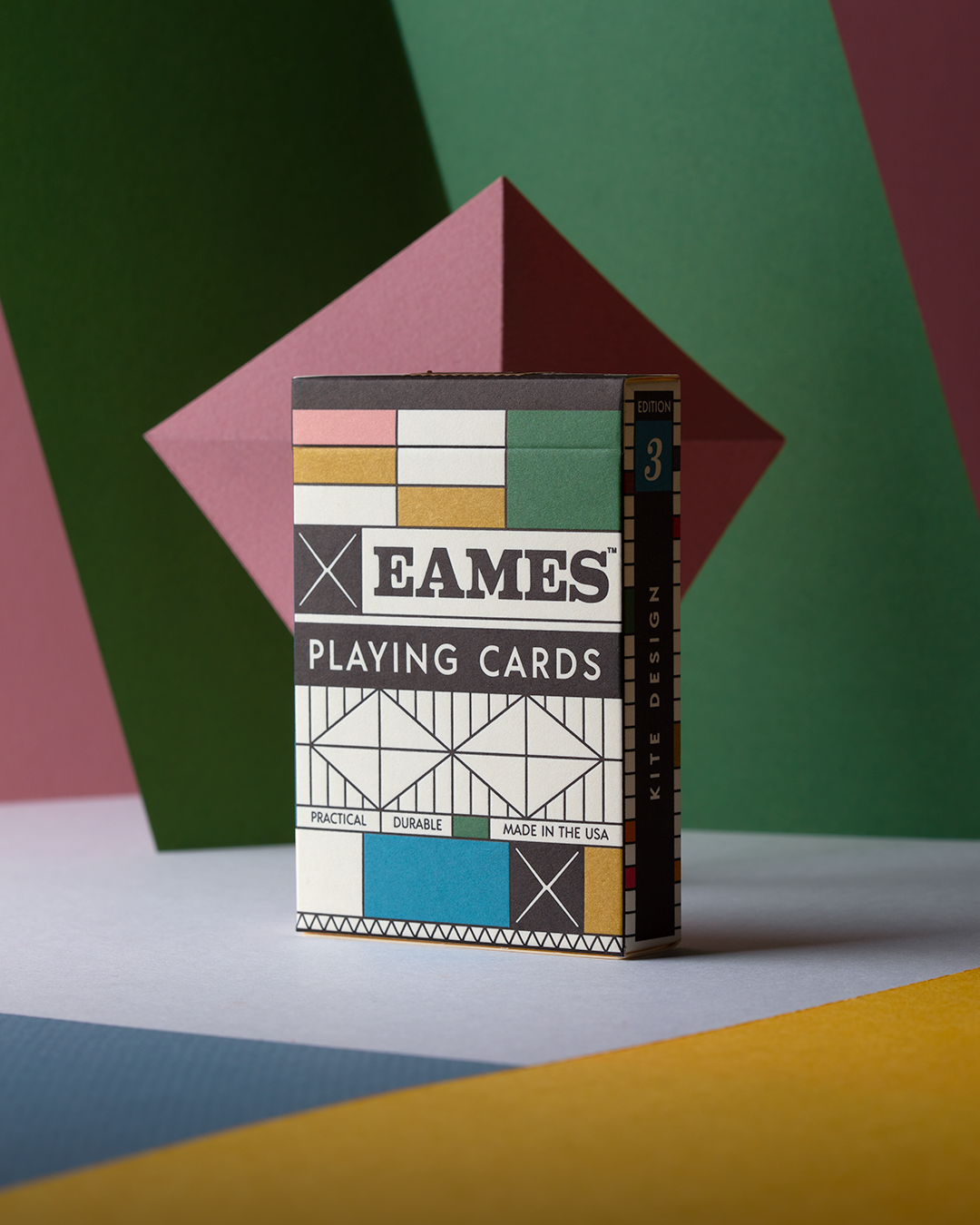 Eames playing cards packaging on a colorful geometric background