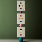 Three playing cards with colorful symbols balanced on a blue sphere against a green background