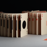 Playing cards arranged in a circular pattern on a gray surface with a black background