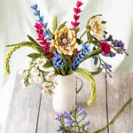 Felt flower bouquet in a mug on a wooden surface with a white background