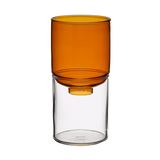 An amber-colored translucent glass vase resting on a clear glass cylinder base, shown against a solid white background.