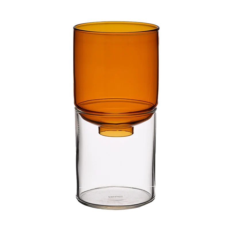An amber-colored translucent glass vase resting on a clear glass cylinder base, shown against a solid white background.