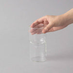 Clear glass vae held by a hand on a gray background