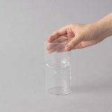 Clear glass vae held by a hand on a gray background
